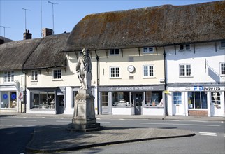 King Alfred statue in the market place and thatched shop buildings in the village of Pewsey,