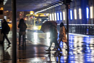 Illuminated subway at the main railway station, pedestrians at a pedestrian crossing, rainy