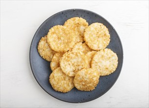 Traditional japanese rice chips cookies with honey and soy sauce on a blue ceramic plate on a white