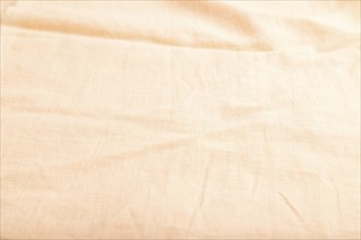 Fragment of smooth orange linen tissue. Side view, natural textile background and texture