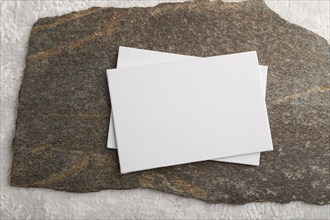 White paper business card, mockup with natural stone on gray concrete background. Blank, flat lay,