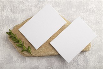 White paper business card, mockup with natural stone and boxwood branch on gray concrete background