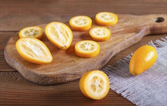 Sliced kumquats on a wooden kitchen board, close up, selective focus