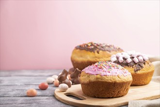 Homemade glazed and decorated easter pies with chocolate eggs and rabbits on a gray and pink