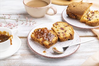 Homemade cake with raisins, almonds, soft caramel and a cup of coffee on a white wooden background