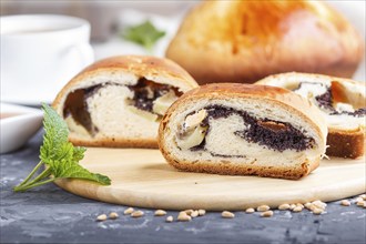 Homemade yeast rolls with poppy seeds and honey on a wooden kitchen board on a black concrete