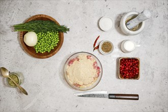 Top view of bowl with minced meat, egg and breadcrumbs surrounded with cranberry and green peas for