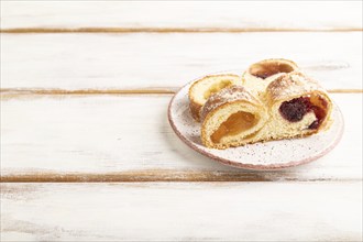 Homemade sweet bun with apricot jam on white wooden background. side view, copy space