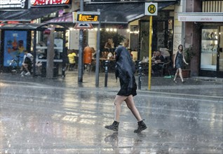 People run across Potsdamer Strasse in heavy rain. After weeks of heat, the first heavy rain