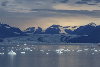 Evening mood with clouds over a glacier, glacier tongue, fjord with icebergs in front of mountains,