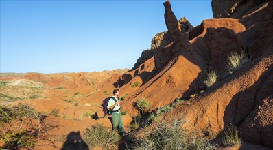 Young man between sandstone rocksErosion landscape of red and yellow sandstone, rock formations at