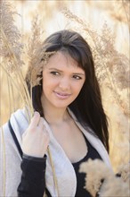 Brunette woman smiling and surrounded by tall dry grass on a sunny day, Bavaria