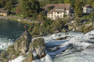 Rhine Falls seen from Laufen Castle, rocky island, Swiss flag, rapids, watermill, Canton Zurich, on