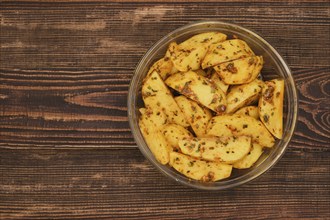 Marinated potato wedges seasoned with herbs, garlic and smoked paprica in a glass bowl