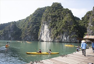 Kayakers start at a jetty, behind them the karst rocks in Lan Ha Bay, Halong Bay, Vietnam, Asia