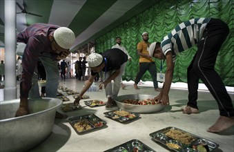 Volunteers distribute and arrange rows of 'iftar' meal for devotees to break their fast, during the