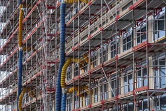 Large construction site, scaffolded shell of an office building complex, air hoses for building