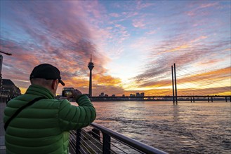 Winter sunset on the Rhine near Düsseldorf, riverside promenade at the old town, Rhine Tower, cargo