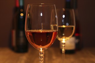 Close-up of two glasses of wine with wine bottles in the background