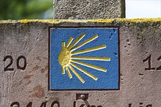 Stone slab with blue shell, showing pilgrims on the Way of St James the way to Santiago de