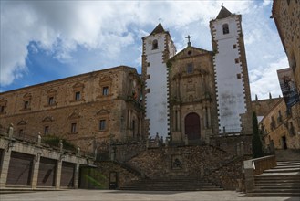 An old church with two towers and a large staircase, surrounded by historic buildings, Iglesia de