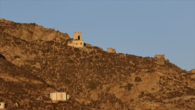 Lonely ruins scattered on a dry hill with minimal vegetation, Colourful mountain village, Morning