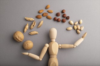 Wooden mannequin juggling nuts on gray pastel background. close up, isolated, delivery concept