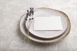 White paper invitation card, mockup with lavender on ceramic plate and gray concrete background.