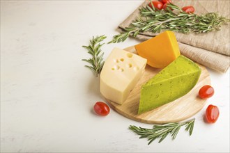 Green basil cheese and various types of cheese with rosemary and tomatoes on wooden board on a