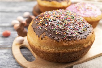 Homemade glazed and decorated easter pies with chocolate eggs and rabbits on a gray wooden