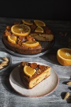 Orange cake on a gray wooden background. Hard light. contrast, low key. Side view, close up