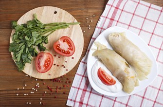 Cabbage rolls with beef, rice and vegetables on a linen tablecloth on a brown wooden background.