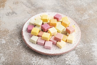 Various fruit jelly chewing candies on plate on brown concrete background. apple, banana,