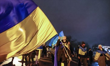 A woman demonstrates with a large Ukrainian flag on the anniversary of the Russian war of