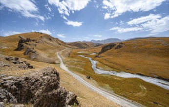 River Kol Suu winds through a mountain valley with hills of yellow grass, Naryn Province,