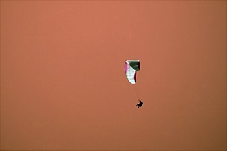 Paragliders in the evening in front of orange-coloured haze from the sunset