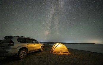 Off-road vehicle and tent, night shot, Milky Way at Lake Issyk Kul, Kyrgyzstan, Asia