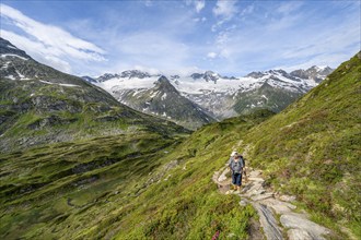 Mountaineer on hiking trail in picturesque mountain landscape, mountain peak with snow and glacier