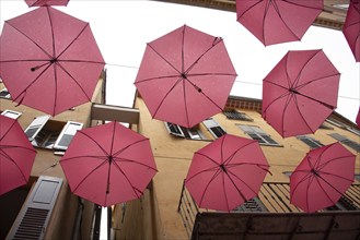 In the perfume town of Grasse, red umbrellas hang between the houses, Grasse, Provence-Alpes-Côte