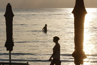 First swimmers at sunrise on the beach of Diano Marina, Italy, 14/08/2024, Diano Marina, Liguria,