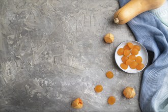 Jelly pumpkin candies on gray concrete background and blue linen textile. copy space, top view,