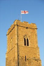 Saint George red and white flag flying against blue sky from church tower, Shottisham, Suffolk,