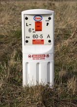 Close up of Esso gas pipeline under surveillance marker warning no dig zone, Salisbury Plain,