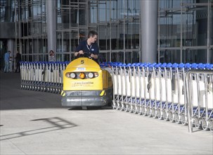 Man driving vehicle collecting trolleys at Malaga airport, Spain, Europe