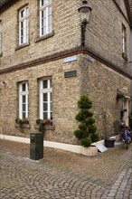 Historic brick house with lantern and mock cypress (Chamaecyparis) at Schweinemarkt in Warendorf,