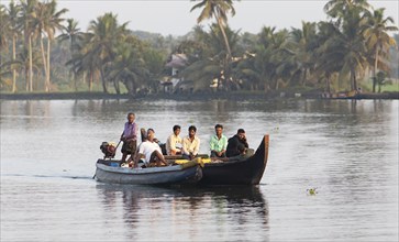 Indian men travelling on a motorboat, canal system of the backwaters, Kerala, India, Asia