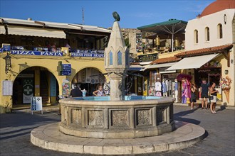 Hippocrates Square, Owl Fountain, Lively market square with a fountain, historic buildings, shops