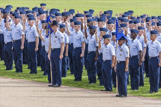 Flight of airmen in dress blues being sworn into service during USAF basic training graduation In