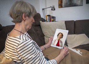 Symbolic image of telemedicine, patient speaking to a doctor in a video conference from home