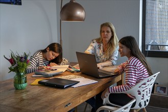 Homeschooling, during the lockdown in January 2021, mother helps her two daughters, at home,